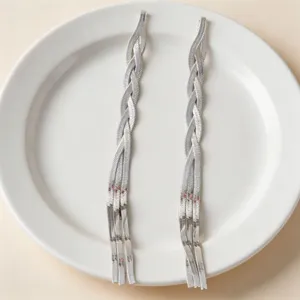 Close-up detail of long silver snake bone chain necklace, minimalist metal jewelry design.