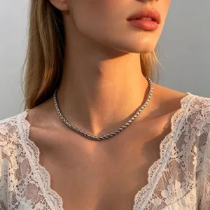 Close-up detail shot of a stylish metallic twisted chain necklace worn gracefully by a model.