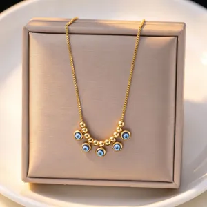 Gold evil eye necklace detail shot, elegant blue bead pendant design on jewelry box display.