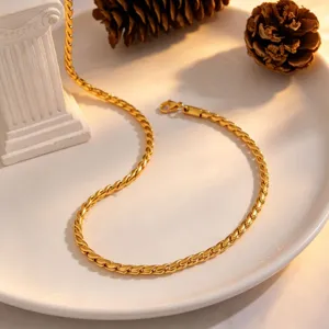 Close-up view of the golden twisted chain necklace beautifully displayed on a white ceramic plate.