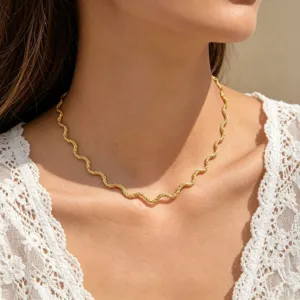 Close-up detail of the elegant wavy chain necklace, showing fine metallic texture and shine.