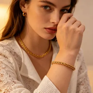 Close up detail shot of stylish gold plated chain bracelet and matching necklace worn by model.
