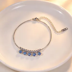 Close-up of a silver-tone stainless steel evil eye charm bracelet with delicate metal beads.
