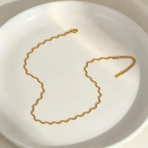Close-up detail of the elegant gold wavy chain necklace showcasing its unique serpentine design.
