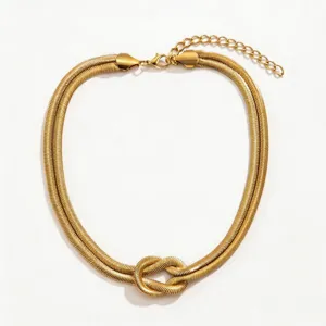Primo piano dettaglio della collana a catena nodata in metallo dorato con bella finitura.