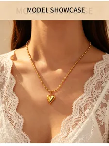 Gold heart pendant necklace detail showcasing beaded chain design and elegant clavicle style.