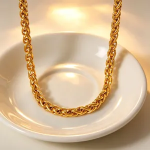 Detailed close-up shot of a thick gold-plated braided chain necklace in a white dish.