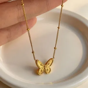 Gold stainless steel butterfly pendant necklace detail shot, delicate bead chain jewelry.