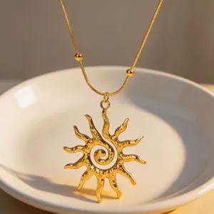 Gold spiral sun pendant necklace with snake chain, elegant fashion jewelry detail shot.