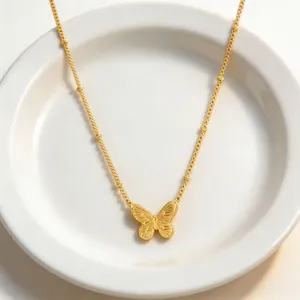 Close-up of golden titanium steel butterfly pendant necklace on white plate, elegant detail.