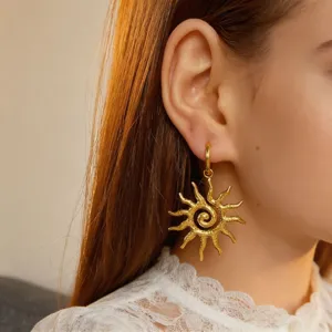 Close-up detail view of the gold spiral sun pendant earring, featuring intricate hollow metal craft.