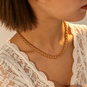 Close-up detail shot of a trendy gold braided chain necklace worn on the neck, elegant style.
