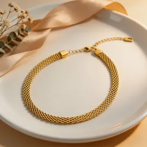 Close-up detail of the elegant gold mesh snake chain necklace on a white ceramic plate.