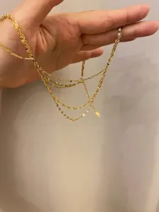 Vue détaillée de l'élégant collier de chaîne dorée à trois couches superposées et fines.