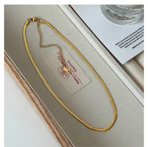 Detailed close-up of a stylish gold-plated herringbone chain necklace displayed on a neat beige tray.
