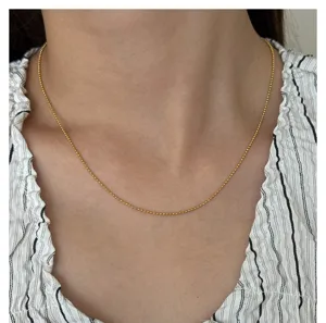 Delicate gold bead chain necklace closeup, elegant stainless steel jewelry for women daily wear.