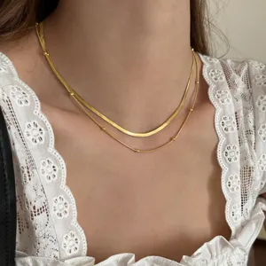 Gold layered herringbone and bead chain necklace closeup detail view showcasing polished finish