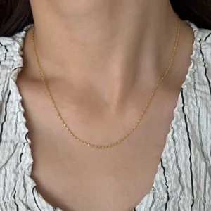 Close-up detail shot of a delicate thin gold-plated stainless steel chain necklace on neck.