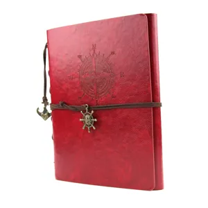 Detail shot of red leather vintage journal notebook with compass embossment and anchor charm.