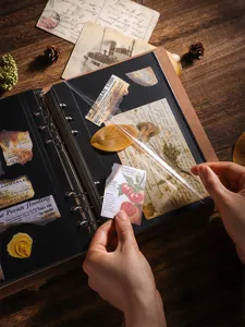 Détail d'un album photo de scrapbooking DIY avec pages noires et stickers rétro sous film protecteur.