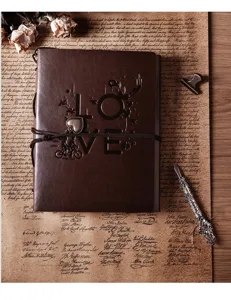 Detailed view of vintage brown leather scrapbook album cover with embossed love design and pen.