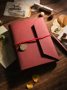 Vue détaillée d'un album photo DIY rouge rétro avec un pendentif horloge et une cordelette.