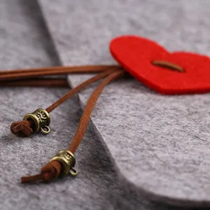 DIY handmade felt photo album cover detail featuring a red heart decoration and leather cords