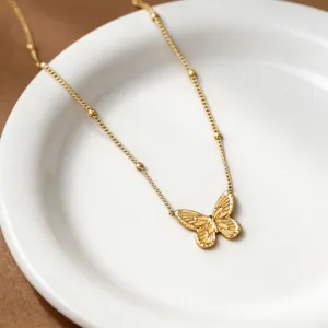 Golden butterfly pendant necklace detail shot showcasing delicate beaded chain and craftsmanship.