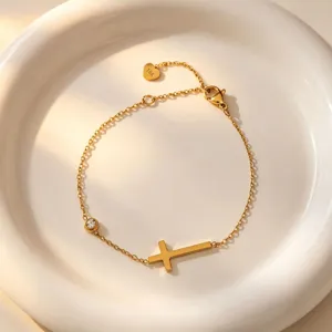 Minimalist 18K gold plated stainless steel cross bracelet with sparkling zirconia stone detail.