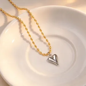 Detail shot of two-tone gold and silver beaded chain necklace showcasing a puffy heart pendant.