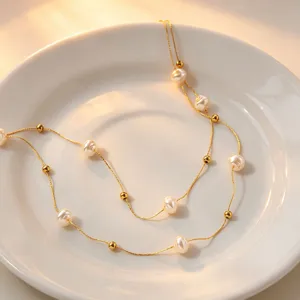 Detailed close-up shot of the double-layer pearl and gold bead necklace on white ceramic plate.