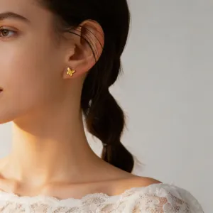 Close-up detail of a delicate gold butterfly stud earring worn on the ear, elegant and chic.