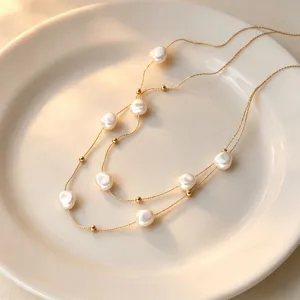 Close-up detail of the elegant double-layer baroque pearl necklace with fine chains.