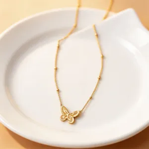 Exquisite gold-tone butterfly pendant detail on delicate beaded chain, stylish jewelry close-up.
