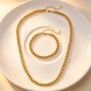 Close-up display of gold stainless steel woven chain necklace and matching bracelet set