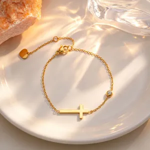 Gold titanium steel cross bracelet detail shot, elegant minimalist luxury fashion accessory.