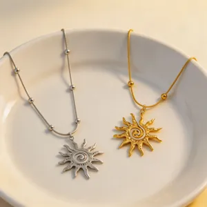 Close-up detail view of gold and silver spiral sun pendant necklaces displayed on a white plate.