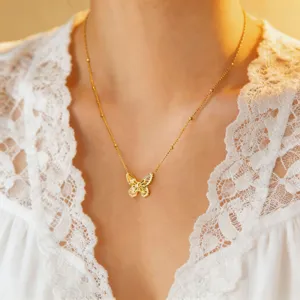 Close-up detail shot of a delicate gold butterfly pendant titanium steel necklace worn on neck.