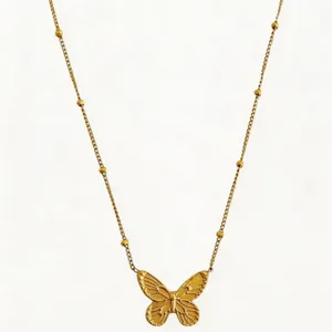 Close-up detail of a delicate gold stainless steel necklace featuring a textured butterfly pendant.