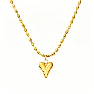 Close-up detail of the glossy gold-toned puffy heart pendant and delicate rice bead chain necklace.