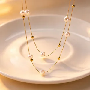 Exquisite close-up of double-layer baroque pearl necklace with delicate gold beads on plate.