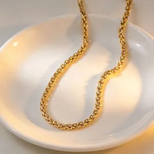 Close-up detail of a delicate gold-toned chain necklace resting elegantly on a white ceramic dish.