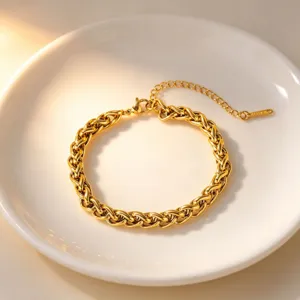 Close-up detail of the elegant gold-plated interlocking chain bracelet on white dish.