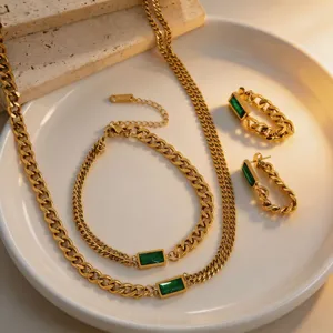 Gold titanium steel necklace bracelet earrings set with green emerald baguette crystal details.