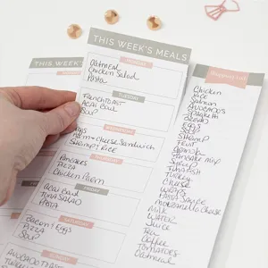Detail view of minimalist weekly meal planner notepad with tear-off shopping list and clean design.