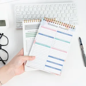 Primo piano del taccuino organizer per matrimoni con rilegatura a spirale e pagine dettagliate.