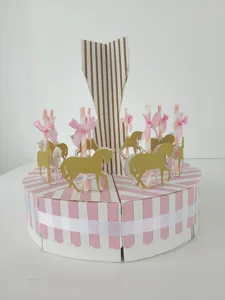 Detailed view of the paper carousel favor box with pink stripes, gold glitter unicorns, and bows.