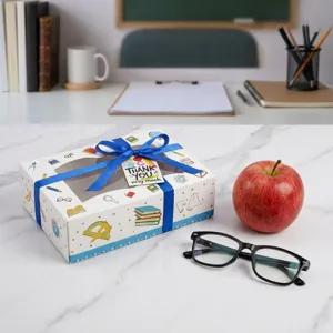 Geschenkbox mit Schreibwaren Muster, blauer Schleife und Dankeschild für Lehrer.