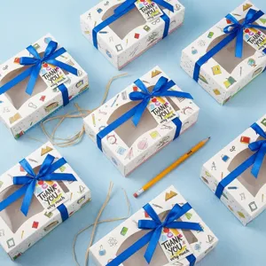 Geschenkboxen mit süßem Schreibwaren Muster, blauen Schleifen und Dankeschön Etiketten.