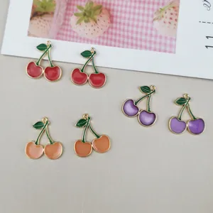 Close-up details of vibrant enamel cherry charms, metal DIY jewelry pendants for craft projects.